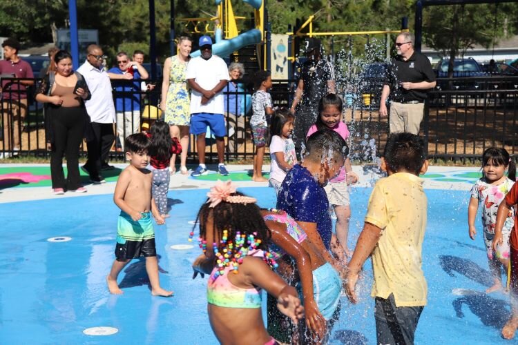 University Area CDC CEO and Executive Director Sarah Combs and board member Ross Fabian look on during the ribbon-cutting celebration for the Harvest Hope Park splash pad in April 2024