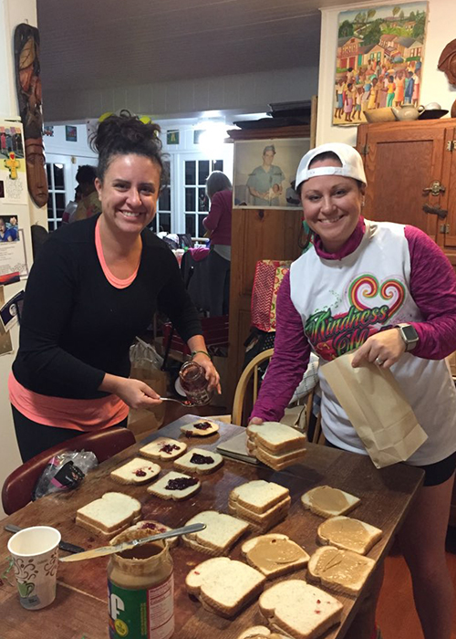Chelsey Crandall and Meaghan Hoy make sandwiches for care bags for the homeless before sunrise in their mother, Dr. Campbell's kitchen.