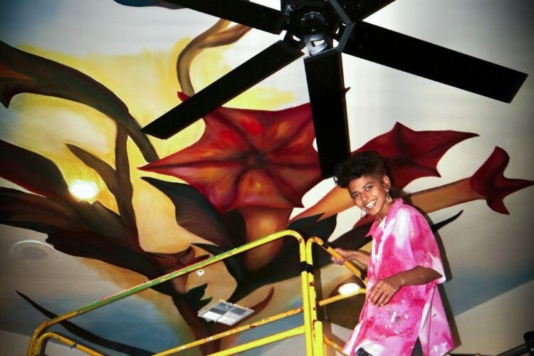 Selena Ferrer works on a ceiling mural at Lector 85 in Ybor City