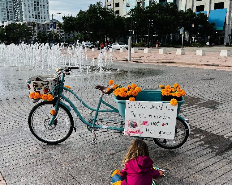 Maya Rabaut, age 5, colors a sign that reads, “Children should have flowers in their hair, not on their graves.”