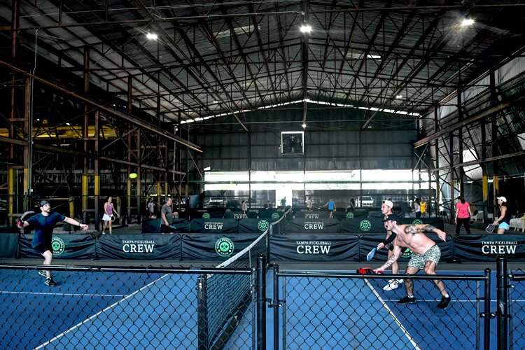 Launched in 2023, Tampa Pickleball Crew is a hive of activiity. Who knew that whacking plastic balls back and forth across a net, under 40-foot ceilings with exposed, oxidized beams, would feel so cool and urban and of-the-moment? 